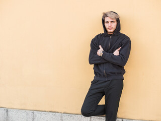 A man leaning against a wall with his arms crossed. Photo of a man with a confident pose leaning against a wall