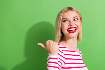 Photo of cheerful woman with bob hairstyle dressed striped shirt look directing at offer empty space isolated on green color background