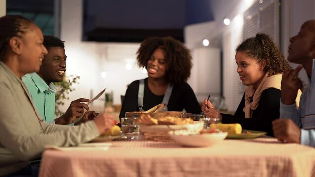 Happy african family eating dinner together at home terrace - Party, bonding and holiday concept