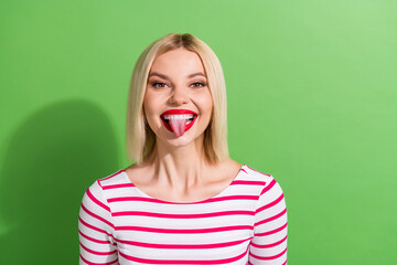 Photo of optimistic funky friendly woman with bob hairdo dressed striped shirt showing tongue fooling isolated on green color background