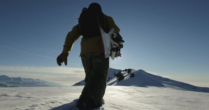 Snowboarder climbs up snow mountain. Tourist athlete with snowboard walks with difficulty, falls through drowns in snowdrifts stubbornly overcomes obstacles goes towards impressions happy emotions