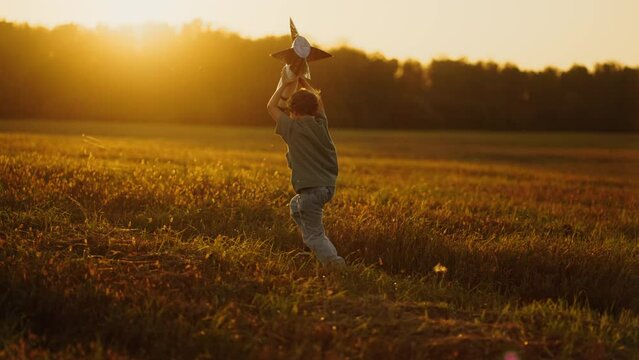 Happy Summertime In Countryside, Child Boy With Toy Rocket Running In Field In Sunset, Slow Motion