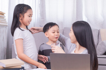 Happy single Asian mom with children playing together bonding relationship, Asian freelancer woman working using modern technology laptop, kids sibling bring glass of dairy milk to mother health care