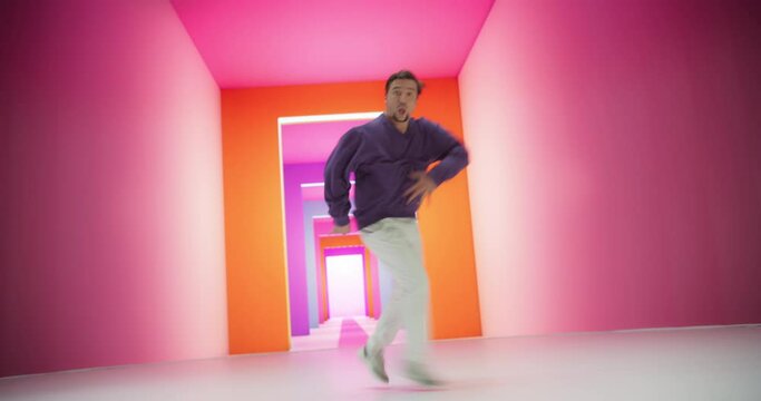 Young And Athletic B-Boy Breakdancing To Break Beats in a Colorful Abstract Neon Lit Studio. Energetic Fashionable Man Practicing Freestyle Choreography For Upcoming Breakdance Battle