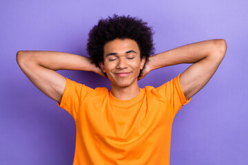 Fototapeta na wymiar Photo of handsome guy youngster wear orange t shirt sleeping hands behind head spend weekend in bed isolated over purple color background
