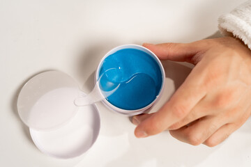 Close-up of man using under eye patches at light table, top view. Cosmetic product