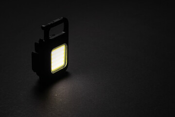 LED Flashlight Keychain and a beam of light in darkness. A modern led lamp with bright projection...