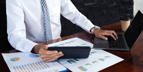 Businessmen bookkeeper hand holding tablets use laptop analysis graphs for Setting challenging business goals and ready to achieve target at home office
