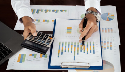 Businessmen bookkeeper hand holding pen and use calculator, laptop analysis the graph for Setting challenging business goals and ready to achieve target at home office