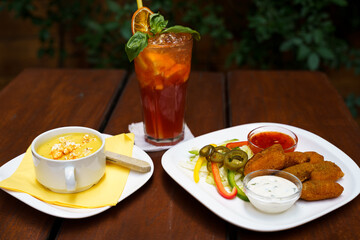 Bowl of sweet corn soup with popcorn and Chicken nuggets with salsa sauce, garlic sauce and vegetables