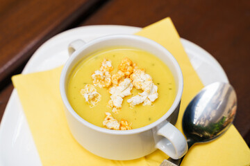 Bowl of sweet corn soup with popcorn on a wooden table