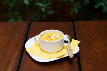 Bowl of sweet corn soup with popcorn on a wooden table