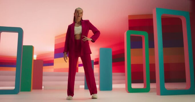 Low Angle Portrait of a Stylish Female Walking Confidently In and Out of a Bright Lit Room. Fashionable Young Woman Performing a Catwalk in a Bright Colorful Studio