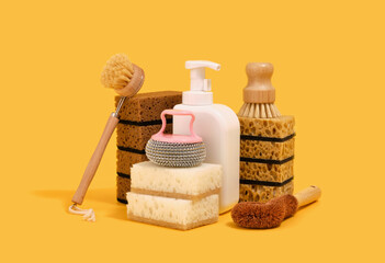 Composition with cleaning supplies for dish washing. Dishwashing gel dispenser, sponges and brushes.