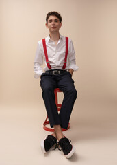 portrait of a young man in a white shirt and red suspenders, glasses, posing for the camera, on a light background