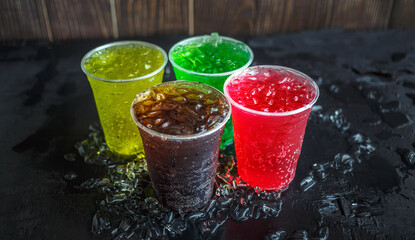 A lot of Soft drinks in colorful and flavorful plastic glasses with ice cubes Chilled on ice on the...