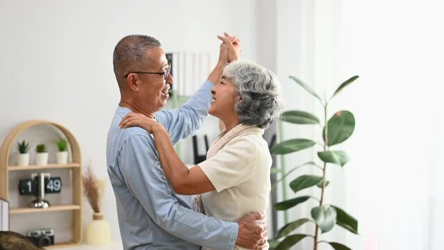 Beautiful senior couple looking at each other with tenderness while dancing together. Elderly lifestyle and marriage concept