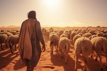 Fotobehang A man is seen walking in the desert accompanied by a herd of sheep. This image can be used to depict concepts such as nomadic lifestyle, animal husbandry, or the challenges of survival in harsh enviro © Fotograf