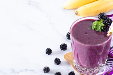 Blackberry banana smoothie with fresh mint on white background. Copy space. Healthy refreshing...