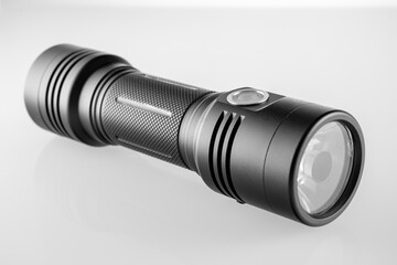 black LED modern handheld flashlight on a white background with reflection, metal durable housing, double-sided, led flashlight, reflexed pen, studio photo