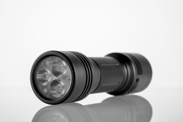 black LED modern handheld flashlight on a white background with reflection, metal durable housing, double-sided, led flashlight, reflexed pen, studio photo