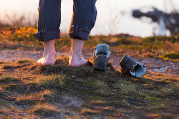 traveler barefoot on the grass, rear view. concept of a long journey, good shoes. Ecology. Copy...