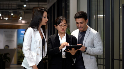 group of diversity business people asian woman and caucasian man walking and talking with using tablet computer going to lunch in office .  appointment to date in meeting