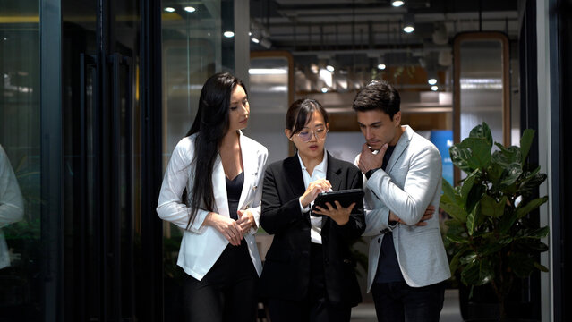 group of diversity business people asian woman and caucasian man walking and talking with using tablet computer going to lunch in office .  appointment to date in meeting