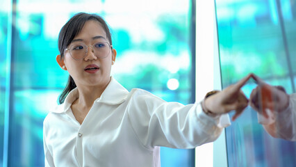 young asian business woman standing in front of television screen giving presentation and Explaining Graphs in office . speaker with whiteboard presenting  idea to colleagues in meeting