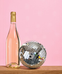 Concept of party and celebration. A glittering disco ball and a bottle of sweet, expensive wine. Copy space for text.