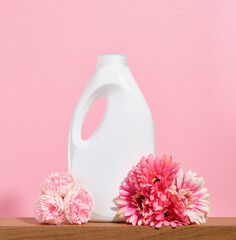 Laundry detergent for white clothes and many colorful spring flowers on a pink background.