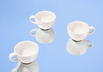 Modern white coffee and tea cups on the mirror. Clean and empty tableware.