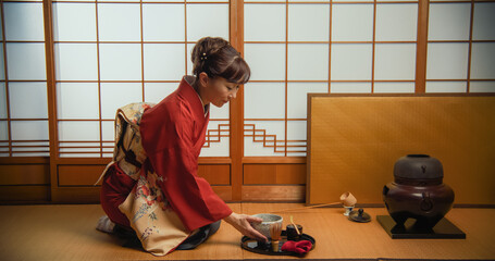Adult Japanese Female Preparing Matcha Green Tea at Home While Sitting on a Tatami Floor. Asian...