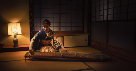 Talented Female Playing Koto Stringed Instrument in Traditional Dark Japanese Home with Lamp....