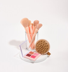 Spa beauty products and makeup professional cosmetics on a round white stand. Luxury makeup brushes, colorful eye shadow and round massage brush.