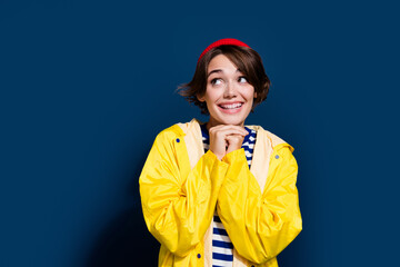 Photo of cute young lady brown bob hair red beanie hat hands together anticipation looking empty space isolated on blue color background