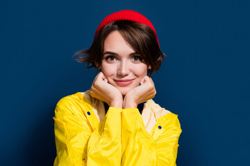 Closeup photo of young girl brown hair touch cheeks posing wear yellow coat dreamy cute outdoors tourist isolated on blue color background