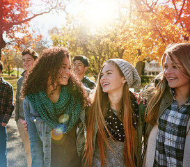 Teenager, walking and talking with friends in park, nature or social group outdoor in autumn with...