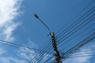 Fototapeta premium Led street light with a cloudy blue sky. Electric pole power lines and wires