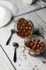 Italian tiramisu dessert in a glass. on a white wooden table. dessert, snack