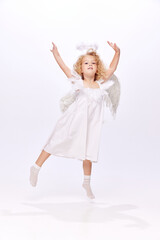 Fototapeta na wymiar Happy, adorable, cute baby girl child in image f angel dancing and handing fun isolated over white studio background. Concept of childhood, imagination, fantasy, fashion and beauty, holidays