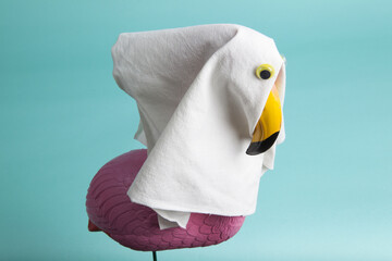 a plastic flamingo decoration disguised as a ghost with a sheet and false eyes