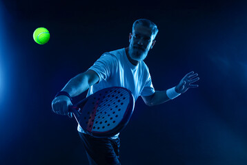 Padel player. Padel tennis open tour. Man athlete with paddle tenis racket and ball on blue...