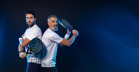 Padel tennis doubles. Two athletes players with racket. Men with paddle racket on court with neon...