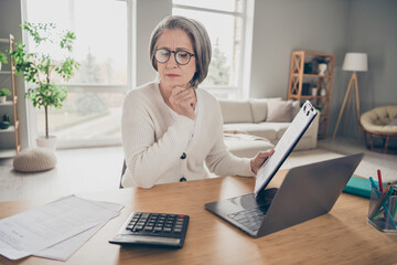 Photo of confident clever senior lady boss dressed white cardigan counting payment modern gadget indoors house room