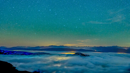 Ciel étoilé en montagne avec des vallées recouvertes de nuages