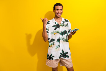 Fototapeta premium Portrait of intelligent nice guy with ring in nose hold smartphone directing at eshop empty space isolated on yellow color background