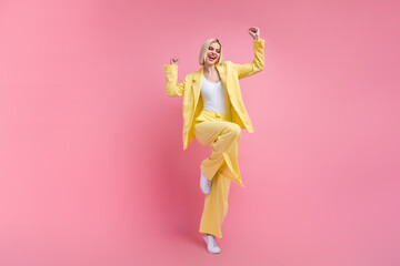 Full size photo of delighted funky girl raise fists shout yes hooray empty space isolated on pink color background