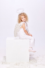 Adorable, cute little girl, child in image of angel, wearing white dress and halo isolated over...