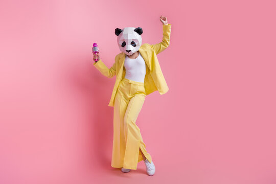 Full size photo of weird 3d panda mask girl elegant costume hold microphone dance empty space isolated on pink color background